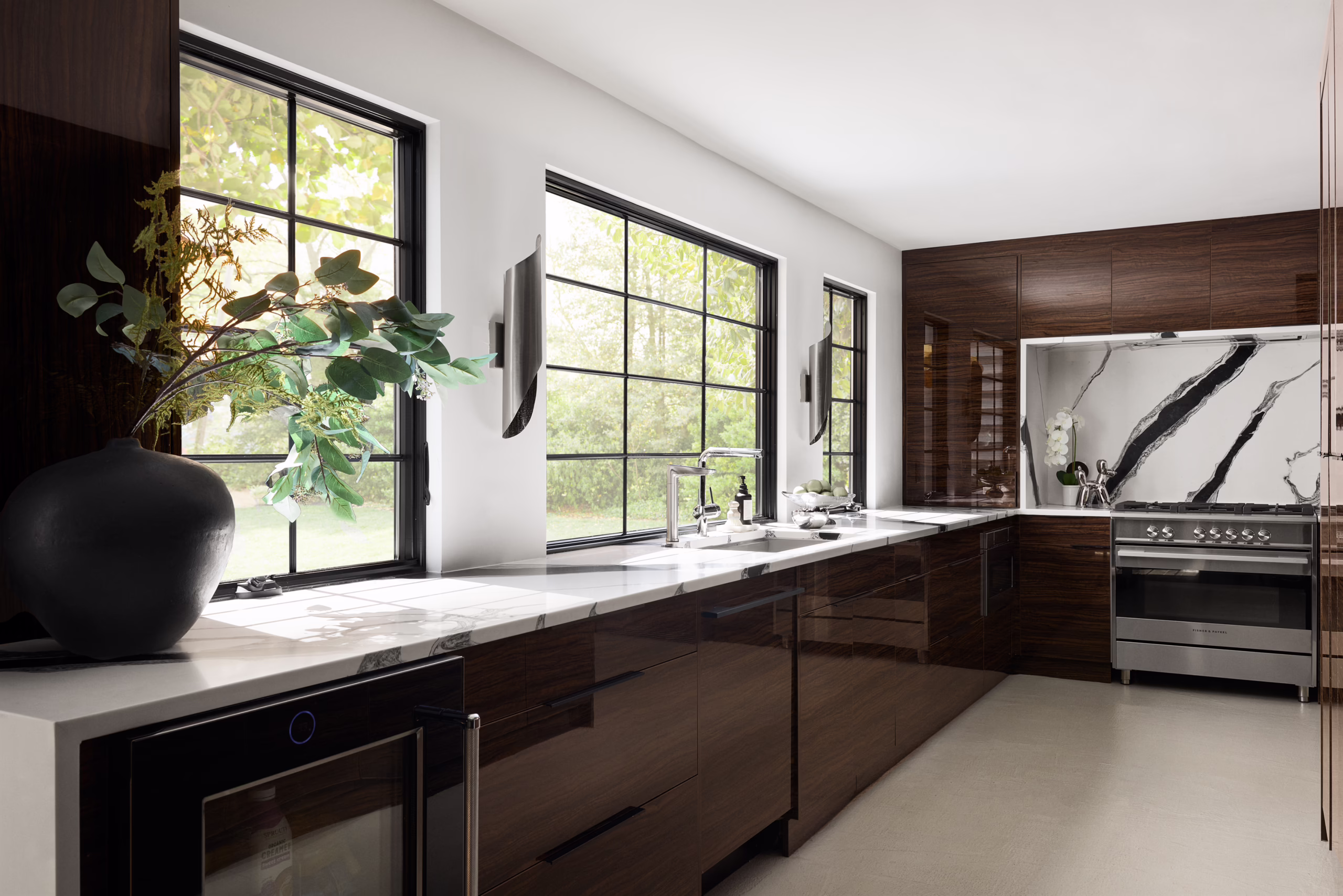 Crest galley kitchen with dark wood cabinetry, marble counters and black framed windows