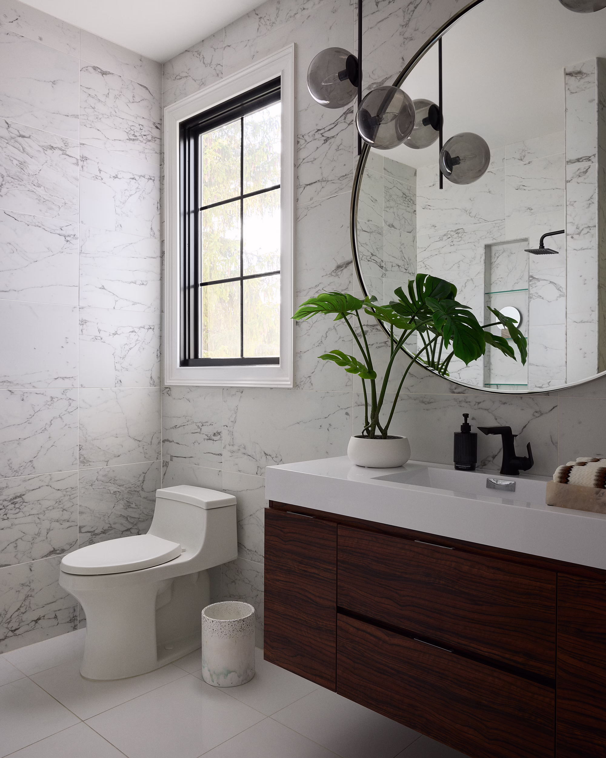 Crest bathroom with marble walls, a floating wood vanity and round mirror
