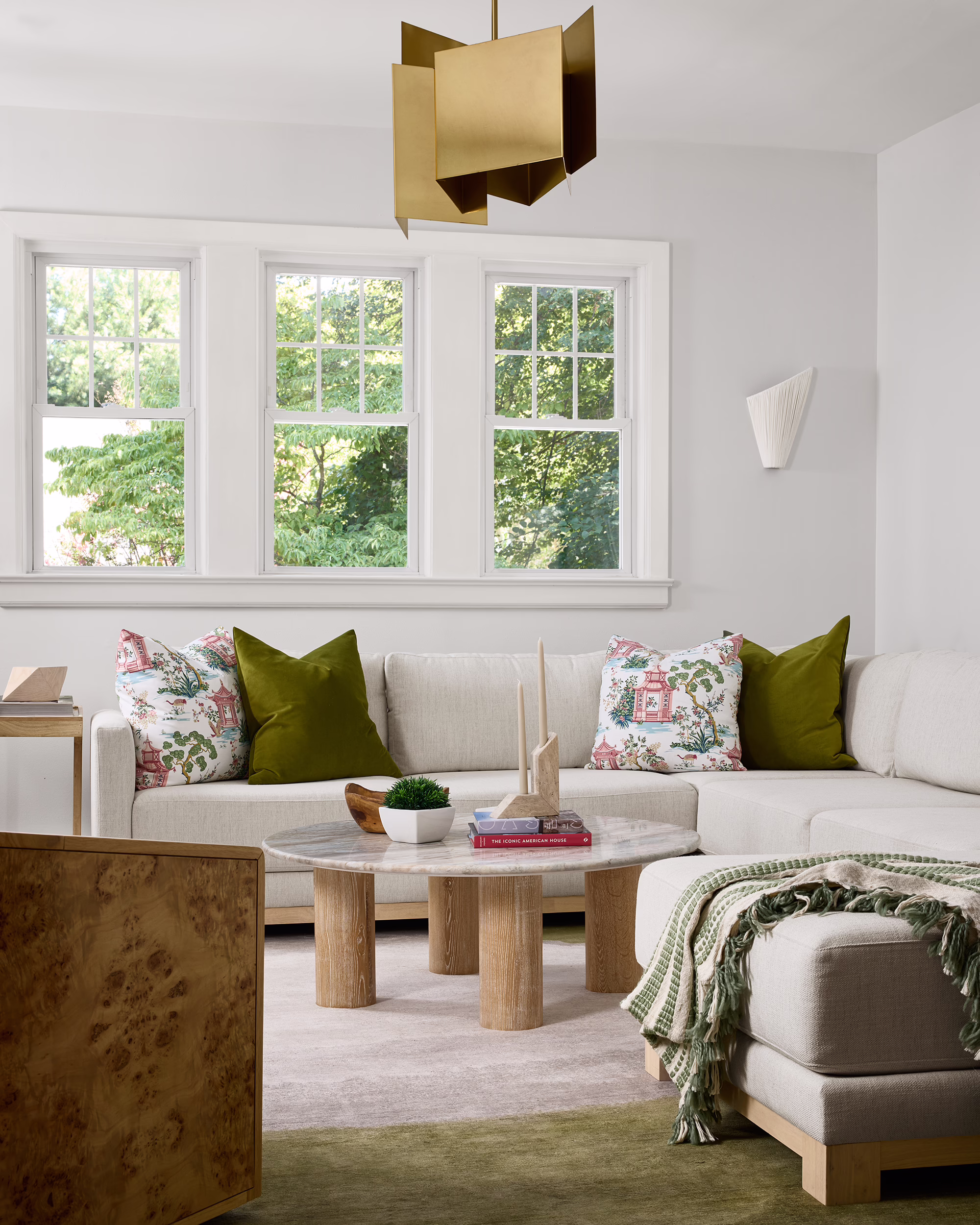 Station living room with a white sectional, green accents and a brass pendant light